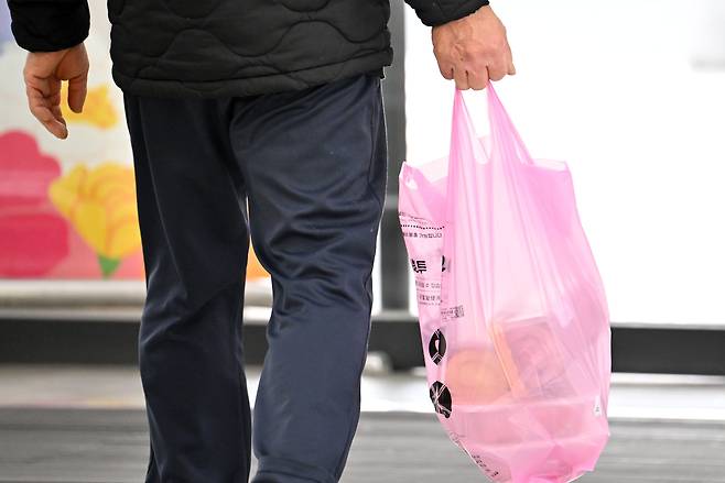 지난달 30일 서울 도심 내 마트에서 한 시민이 종량제 봉투에 구매한 물건을 담아 가고 있다. 최근 나프타 공급 불안정 기류로 인해 종량제 봉투 등 비닐류 품절 사례가 전국 곳곳에서 발생하고 있는 가운데 이날 김성환 기후에너지환경부 장관은 SNS를 통해 지방정부의 절반 이상이 6개월 치 물량을 확보하고 있으며, 원료 또한 1년 이상 공급이 가능하다고 밝혔다. 임세준 기자