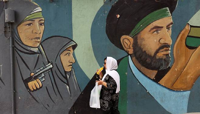 위 사진은 기사 내용과는 직접 관련 없음. 2025년 5월 21일 한 이란 여성이 이슬람 혁명수비대(IRGC) 병사들이 그려진 벽화를 지나가고 있다. (사진=EPA연합뉴스)