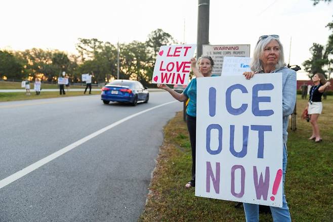 미국 해병대 훈련소인 사우스캐롤라이나주 패리스아일랜드에서 수료식이 진행된 3일(현지시간) 시위대가 이민세관단속국(ICE)의 활동 중단과 구금 시설 폐쇄를 요구하고 있다. 도널드 트럼프 행정부는 2027 회계연도 예산안에 군 시설을 구금 시설로 활용할 수 있도록 하는 내용을 포함했다. 로이터 연합
