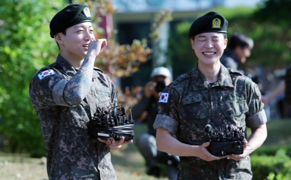 육군 병장으로 만기 전역한 BTS 지민과 정국이 11일 경기 연천군 연천공설운동장에서 열린 기념행사에서 팬들에게 인사하며 웃고 있다.