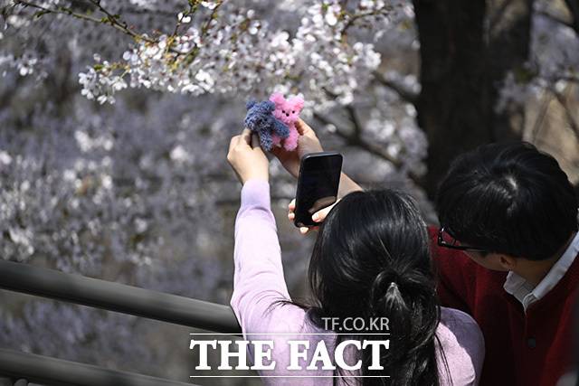 한 커플이 인형과 사진을 찍고 있다.