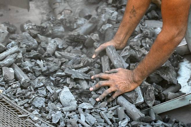 지난 27일(현지시간) 이란 전쟁으로 석유가스 수입이 차질을 빚는 가운데, 인도 아마다바드 석탄 저장소에서 노동자가 하역된 석탄을 분류하고 있다. (사진=AFP)