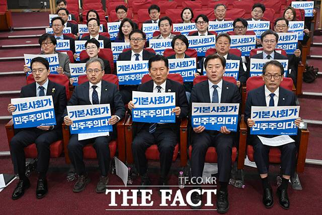 정청래 더불어민주당 대표(가운데)를 비롯한 참석자들이 7일 오전 서울 여의도 국회 의원회관에서 열린 민주당 기본사회위원회 3기 출범식에서 손피켓을 들고 구호를 외치고 있다. /국회=서예원 기자