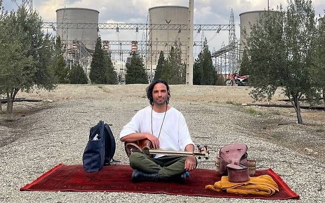6일(현지시각) 이란 음악가 알리 감사리가 수도 테헤란의 발전시설 다마반드 발전소 앞에 앉아 있다. 알리 감사리 텔레그램 계정