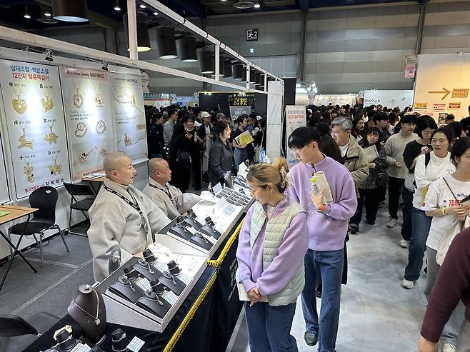Ven. Ilseo (right, background) observes visitors from his booth, which features Buddhist jewelry at the 2026 Seoul International Buddhism Expo. (Tammy Park/The Korea Herald)