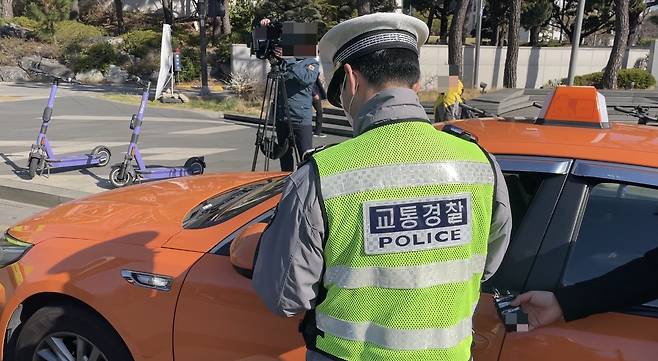 7일 오전 서울 서대문구 연세대 교차로에서 교통 경찰이 신호위반을 한 택시 기사에게 범칙금을 부과하는 모습./사진=이현수 기자.