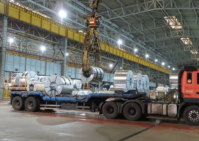 전남 광양제철소 제품 창고에서 무인 크레인이 철강 코일을 들어 올려 트레일러에 상차하고 있다.  [포스코플로우 제공]