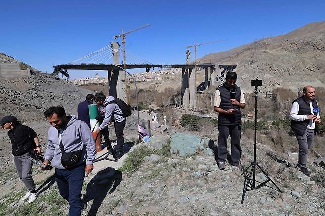3일(현지 시간) 이란 테헤란에서 남서쪽 떨어진 카라지에서 미군의 공습으로 파괴된 고속도로 교량 앞에 현지 언론사 대표들이 모인 모습. AFP연합뉴스