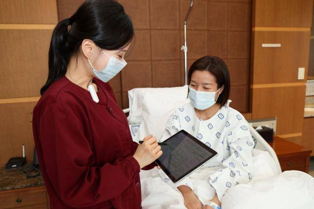 서울성모병원 간호사가 태블릿을 활용하여 환자와 모바일 간호정보를 확인하고 있다.[사진=서울성모병원]