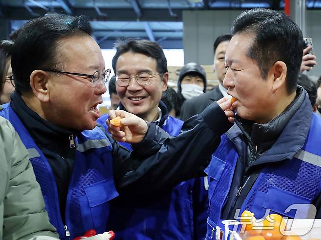 8일 오전 대구 북구 대구농수산물도매시장에서 민생 현장 체험에 나선 정청래 더불어민주당 대표와 대구시장 선거에 출마한 김부겸 전 총리가 경매사의 안내를 받아 경매에서 낙찰된 수입산 감귤을 맛보고 있다. 정 대표는 1965년생, 김 전 총리는 1958년생으로 김 전 총리가 7살 많다. 2026.4.8 ⓒ 뉴스1 공정식 기자