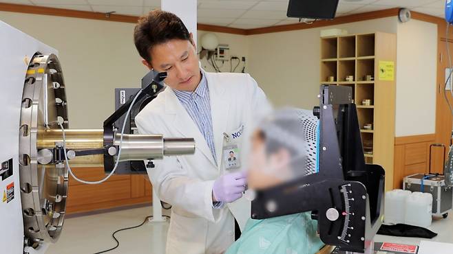 문성호(왼쪽) 국립암센터 양성자치료센터장이 피부암 일종인 맥락막흑색종 환자에게 양성자 치료를 시행하고 있다./사진=국립암센터