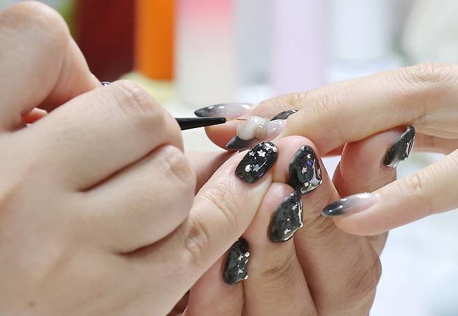 2일 서울 강남구 세텍에서 열린 ‘2025 네일엑스포’의 한 부스에서 관계자가 참관객에게 네일아트를 해주고 있다. [연합]