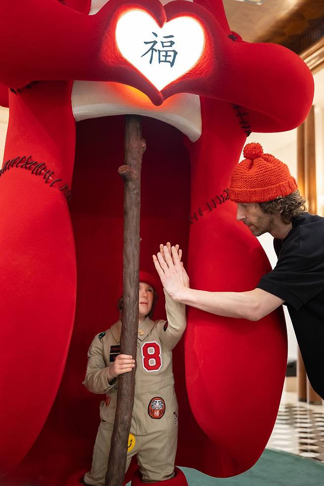 아이 동상과 하이파이브를 하면 용이 들고 있는 하트에 불이 들어온다. 사진 속 하이파이브 하고 있는 사람은 '럭키 드래곤' 작품을 만든 아티스트 프랭키. 사진 로즈우드 홍콩