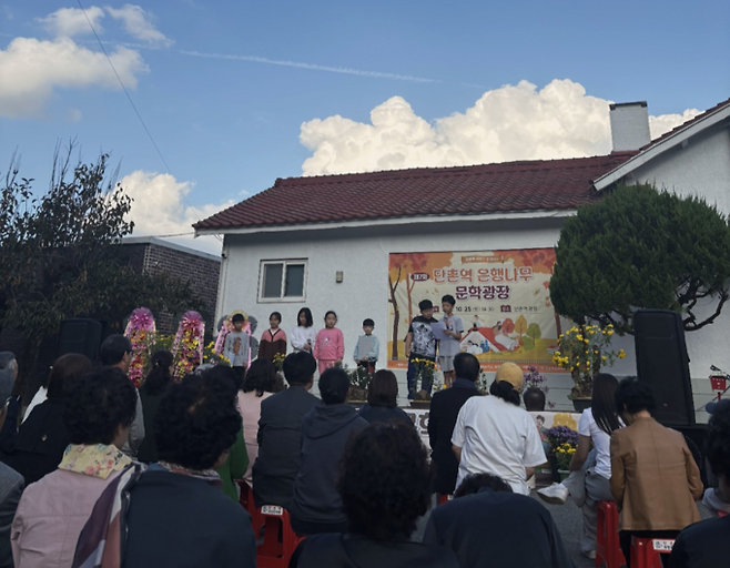 ▲ 2025년 10월 의성군 단촌역에서 열린 '제7회 단촌역 은행나무 문학광장'에서 하율 오르베타 학생(무대 위 맨오른쪽)이 영어 시 'Flower(백두대간 꽃)'를 낭송하고 있다. 정재근 작곡가 제공