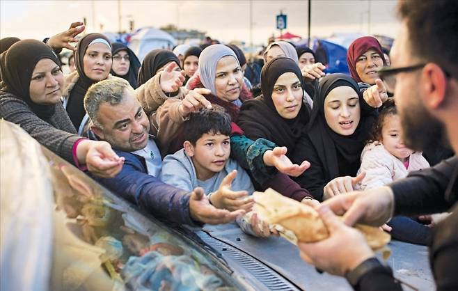 < 폭격 맞은 레바논…“먹을 것 좀 주세요” > 레바논 수도 베이루트에서 9일(현지시간) 폭격으로 거처를 잃은 이재민들이 구호 식량을 받기 위해 앞다퉈 손을 내밀고 있다. 레바논 보건부는 이날 이스라엘의 대규모 공습으로 303명이 사망했다고 밝혔다.  /AP연합뉴스