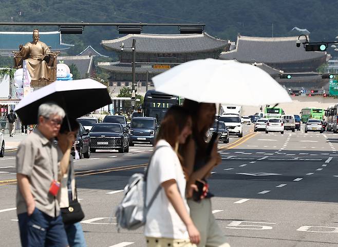 무더위가 이어지고 있는 5일 서울 종로구 광화문광장 인근에서 시민들이 양산을 쓰고 이동하고 있다.[연합]