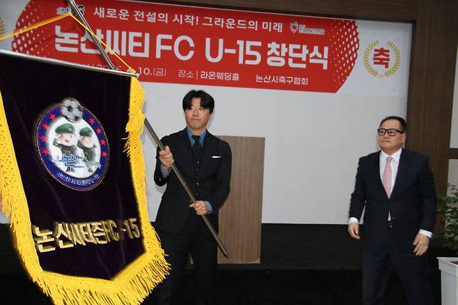 윤충재 단장(오른쪽)으로부터 창단기를 전달받은 안상현 감독(왼쪽)이 새로운 출발을 다짐하며 힘차게 창단기를 흔들고 있다.(논산=장병일 기자)