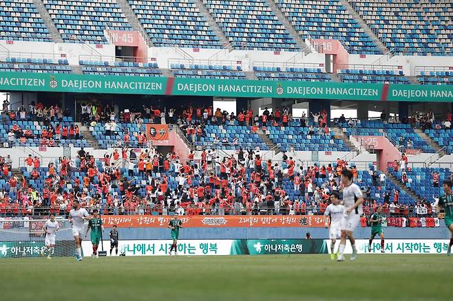 경기장에 등을 돌리고 서서 어깨동무하는 ‘포즈난 응원’을 하고 있는 강원 응원단. 강원은 12일 대전에 2-0 완승을 거뒀다. 한국프로축구연맹 제공
