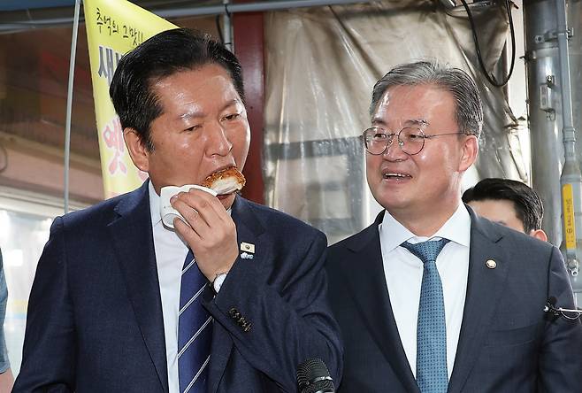 더불어민주당 정청래 대표가 25일 충북 충주시 재래시장인 자유시장을 방문, 한 시장 상인이 건넨 닭다리 튀김을 맛보고 있다. 오른쪽은 이연희 전략기획위원장, 2026.3.25 연합뉴스