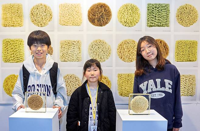 라면을 모티브로 한 작품과 다양한 라면의 면을 찍은 사진들 앞에서 기념사진을 촬영한 소중 학생기자단.