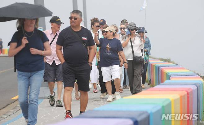 [제주=뉴시스] 우장호 기자 = 제주 해안가를 중심으로 짙은 안개가 드리워진 12일 오전 제주시 무지개해안도로를 찾은 외국인 관광객들이 산책로를 걸어가고 있다. 2024.06.12. woo1223@newsis.com