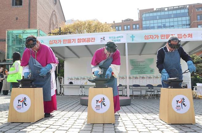 '철조망 십자가 프로젝트' 시연 [2027 서울 세계청년대회 조직위원회 제공. 재판매 및 DB 금지] 이경상 주교, 정순택 대주교, 박용만 이사장(왼쪽부터)이 지난 12일 명동대성당에서 열린 '철조망 십자가 프로젝트' 개막식에서 철조망을 두드려 펴는 시연을 하고 있다. 2025.4.13