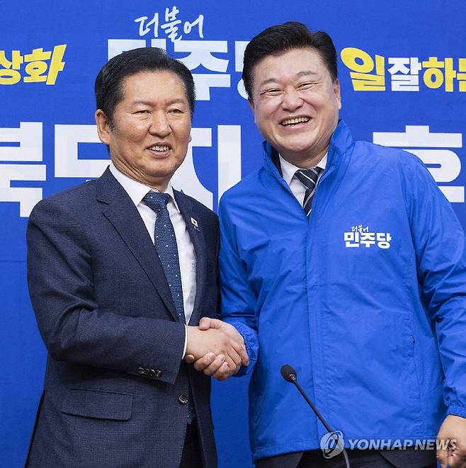 연합뉴스/ 더불어민주당 충북도지사 후보로 확정된 신용한 대통령 직속 지방시대위원회 부위원장이 14일 국회에서 열린 환영식에서 정청래 대표가 전달한 파란색 당 점퍼를 입은 뒤 악수하고 있다.