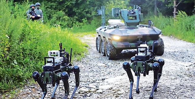An Army Tiger pilot brigade combat team conducts a crewed-uncrewed integrated combat experiment using a pair of quadruped robots (front) and a multipurpose uncrewed ground vehicle. (Army)