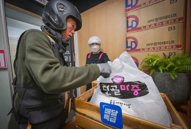 14일 부천시 중동사랑시장 배송센터에서 배달을 위해 포장된 밀키트 제품들을 배달원이 수령하고 있다. 윤원규기자