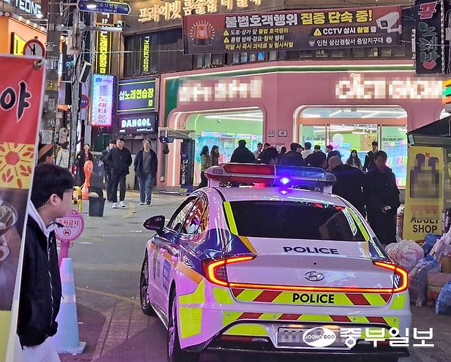 지난 주말 배너 뒤에서 오른쪽 귀에 무전기 이어폰을 꽂은 채 대기하던 한 호객꾼이 경찰의 단속 상황을 주시하고 있다. 사진=심형식 기자