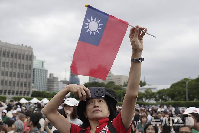 [타이베이=AP/뉴시스] 2024년 10월 10일 대만 타이베이에서 열린 제113주년 쌍십절 국경일 축하 행사에서 대만 국기를 든 남성이 총통 관저 앞에서 셀카를 찍고 있다. 2026.04.15