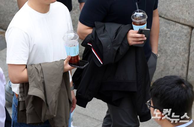 서울 중구 청계천을 찾은 시민들이 재킷을 손에 든 채 아이스아메리카노를 마시며 산책하고 있다. 황진환 기자