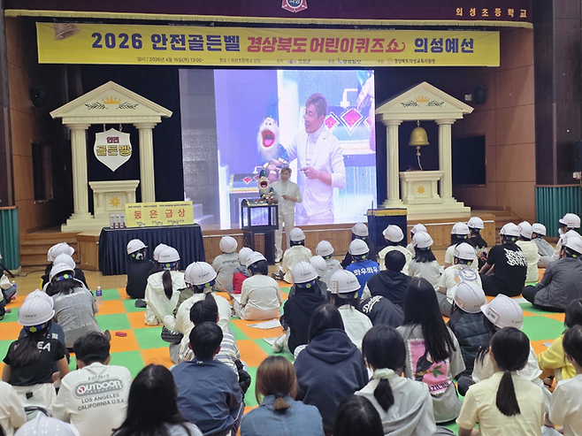 ▲ 16일 의성초등학교 강당에서 열린 '2026 안전골든벨 의성 예선'에서 매직데이컴퍼니 이경창 원장이 식전 마술 공연을 선보이자 학생들이 안전모를 쓴 채 무대를 바라보며 집중하고 있다. 공연은 본격적인 퀴즈에 앞서 긴장된 분위기를 완화하고 현장 몰입도를 끌어올렸다. 김동현 기자 jhass80@kyongbuk.com