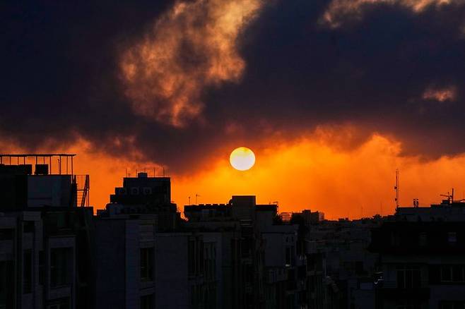 [테헤란=AP/뉴시스] 3일(현지 시간) 이란 테헤란에서 미국과 이스라엘의 군사 공격 이후 치솟는 연기 뒤로 해가 지고 있다. 2026.03.04