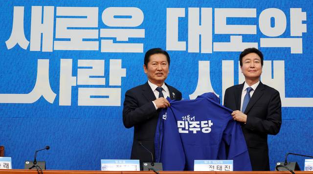 더불어민주당 정청래 대표와 전태진 변호사가 17일 국회에서 열린 1차 인재영입식에서 파란색 당 점퍼를 들고 기념촬영을 하고 있다. 연합뉴스