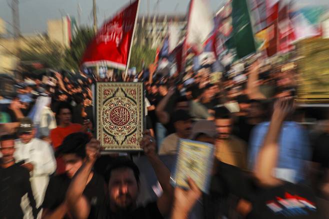 2023년 7월, 이라크 바스라에서 열린 집회에서 무슬림들이 스웨덴에서 발생한 쿠란 소각 사건에 항의하며 쿠란을 들어 보이고 있다. AP 연합뉴스