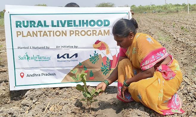 기아가 인도에서 진행 중인 기후변화 대응 사회공헌 프로그램 ‘우파르 캠페인’에 참가한 현지 여성이 황무지에 묘목을 식재하고 있다. [현대자동차그룹 제공]