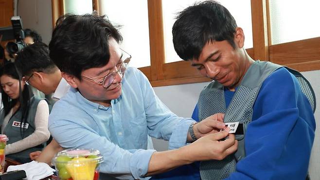 [서울=뉴시스] 김영훈 고용노동부 장관이 지난해 8월 8일 전북 완주군의 외국인 고용 농가를 방문해 간담회에 앞서 외국인 노동자에게 한글 이름표를 붙여주고 있다. (사진=고용노동부 제공) 2025.08.08. photo@newsis.com *재판매 및 DB 금지