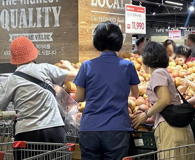 지난해 7월 서울 서초구 킴스클럽 강남점 매장을 찾은 소비자들이 ‘못난이 왕사과’를 고르고 있다. 이랜드 제공