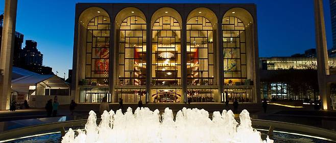 뉴욕 링컨센터 메트로폴리탄 오페라 하우스 야경. 분수대 너머 아치형 유리 파사드 안쪽으로 마르크 샤갈의 대형 벽화 2점, '음악의 승리'(The Triumph of Music, 왼쪽)와 '음악의 원천'(The Sources of Music)이 보인다. [메트로폴리탄 오페라 홈페이지 캡처]