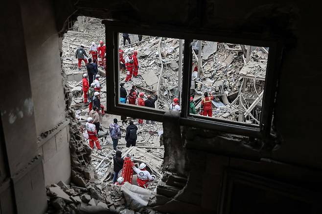 미국과 이스라엘의 공습으로 무너진 이란 테헤란의 한 건물 잔해에서 구조대원들이 16일(이하 현지시간) 긴급 구호활동을 펼치고 있다. 에피 데프린 이스라엘군 대변인은 15일 “최소 3주간 추가 작전이 진행될 것”이라고 밝혔다. 로이터=연합뉴스