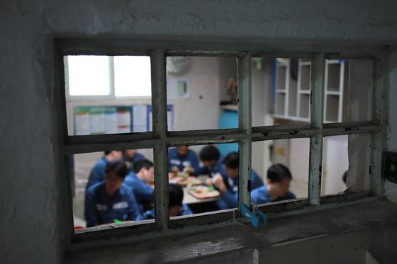 창살 안으로 '수용자 체험' 기자단이 식사를 하고 있다. 식사는 '거실' 안에서 이뤄진다. 식판과 수저 모두 플라스틱이고 식사 뒤 설거지는 안쪽 화장실에서 이뤄진다.〈사진=법무부 제공〉