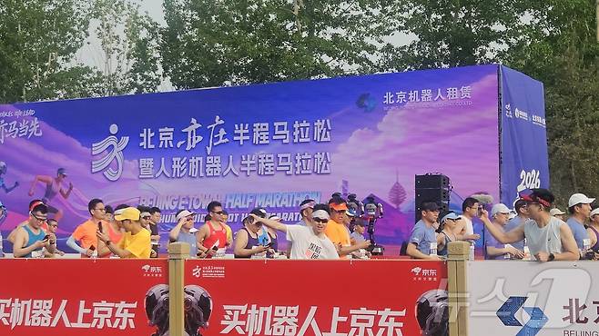 19일 오전 7시 30분 베이징에서 개최된 '제2회 베이징 이좡 휴머노이드 로봇 하프마라톤' 참가자들이 로봇들이 달리는 장면을 지켜보고 있다. ⓒ 뉴스1 정은지 특파원