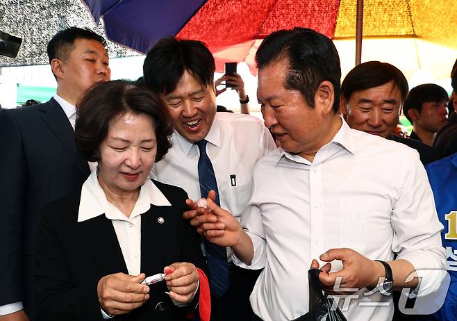 정청래 더불어민주당 대표가 19일 오후 경기 성남시 모란시장 민속5일장에서 김용 전 민주연구원 부원장에게 사탕을 전달하고 있다. (공동취재) 2026.4.19 ⓒ 뉴스1 이승배 기자