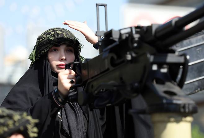 지난 17일 이란 테헤란에서 열린 반미, 반이스라엘 집회에서 한 이란 여성이 군용 차량에 탄 채 기관총을 쥐고 겨누고 있다. EPA=연합뉴스