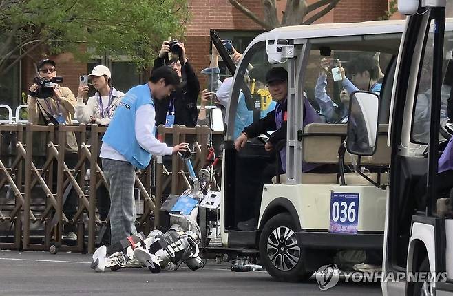 쓰러진 휴머노이드 (베이징=연합뉴스) 김현정 특파원 = 19일 중국 베이징시 이좡에서 개최된 '제2회 휴머노이드 로봇 하프마라톤 대회'에 참가한 한 로봇이 회전로를 돌지 못하고 울타리에 부딪혀 쓰러져있다. 2026.4.19 hjkim07@yna.co.kr