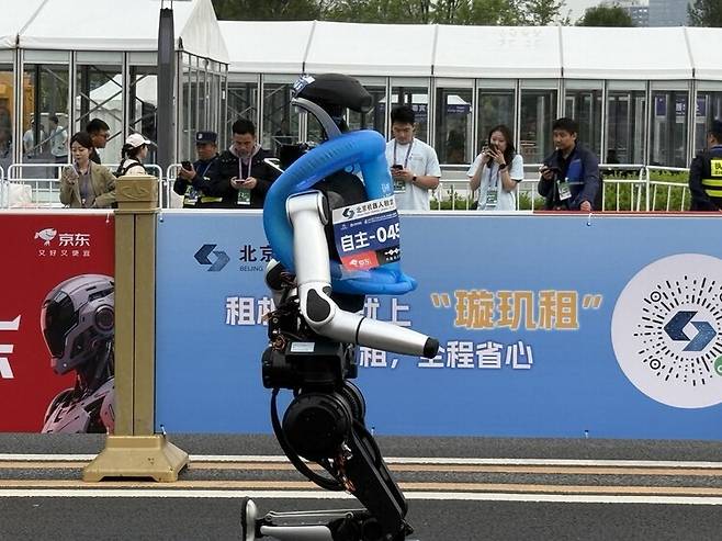 19일 ‘2회 베이징 이좡 인간형 로봇 하프마라톤 대회’에 참가한 로봇이 넘어질 것을 대비해 충격 흡수 장치를 장착하고 달리고 있다. 베이징/이정연 특파원
