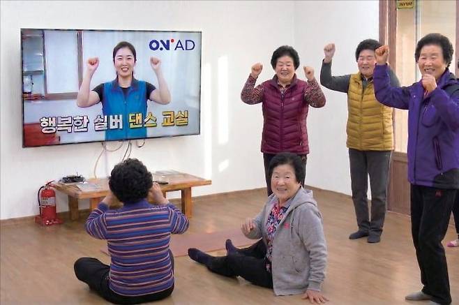 SK브로드밴드 ‘B tv 온애드’가 설치된 경로당에서 노인들이 댄스 교실에 참여하고 있는 모습을 연출한 인공지능(AI) 생성 사진. /SK브로드밴드 제공