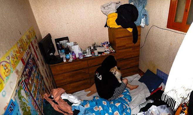 취재팀이 방문한 지난달 27일 경기 성남시 한 달동네 반지하방에서 수빈(가명·20)이 반려견을 안은 채 등을 돌리고 앉아 있다. 방 안 곳곳에 쓰레기봉투와 생활용품이 뒤엉켜 있다. 유희태 기자