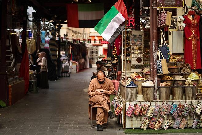 13일 두바이 올드 수크에서 한 가게 주인이 뉴스를 확인하고 있다. /연합뉴스